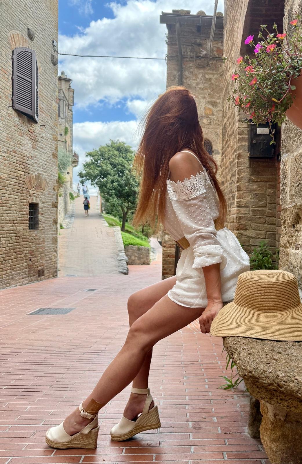 Kobieta w białym stroju w urokliwej uliczce San Gimignano