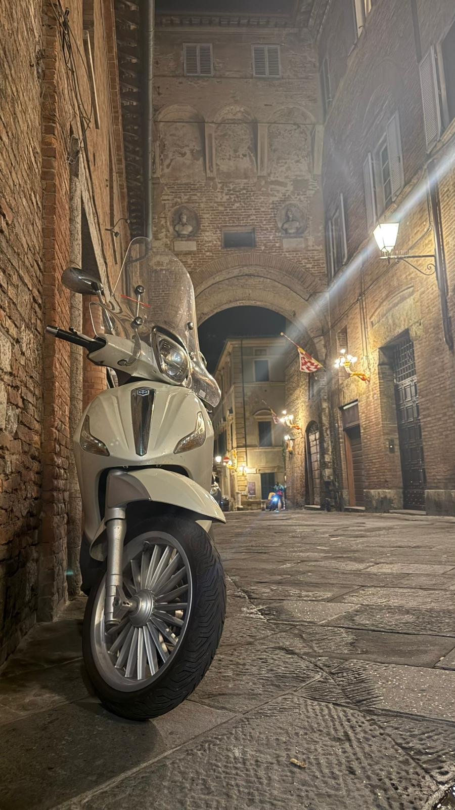 Zabytkowy skuter w nocnej uliczce Sieny