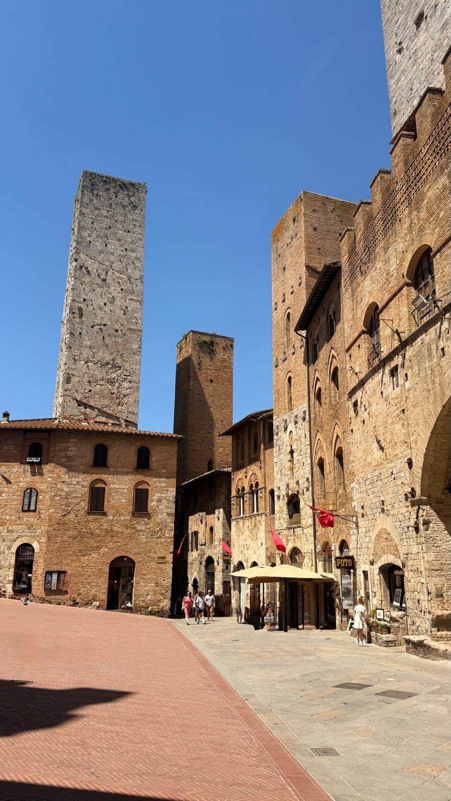 Uliczka San Gimignano z widokiem na wieże i czerwone flagi